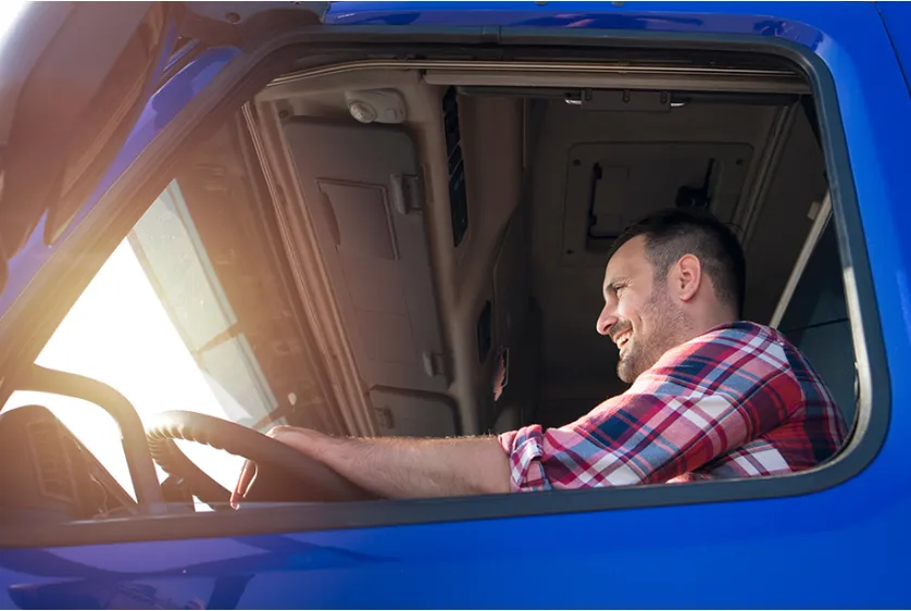 A person is driving a truck with a smile on his face