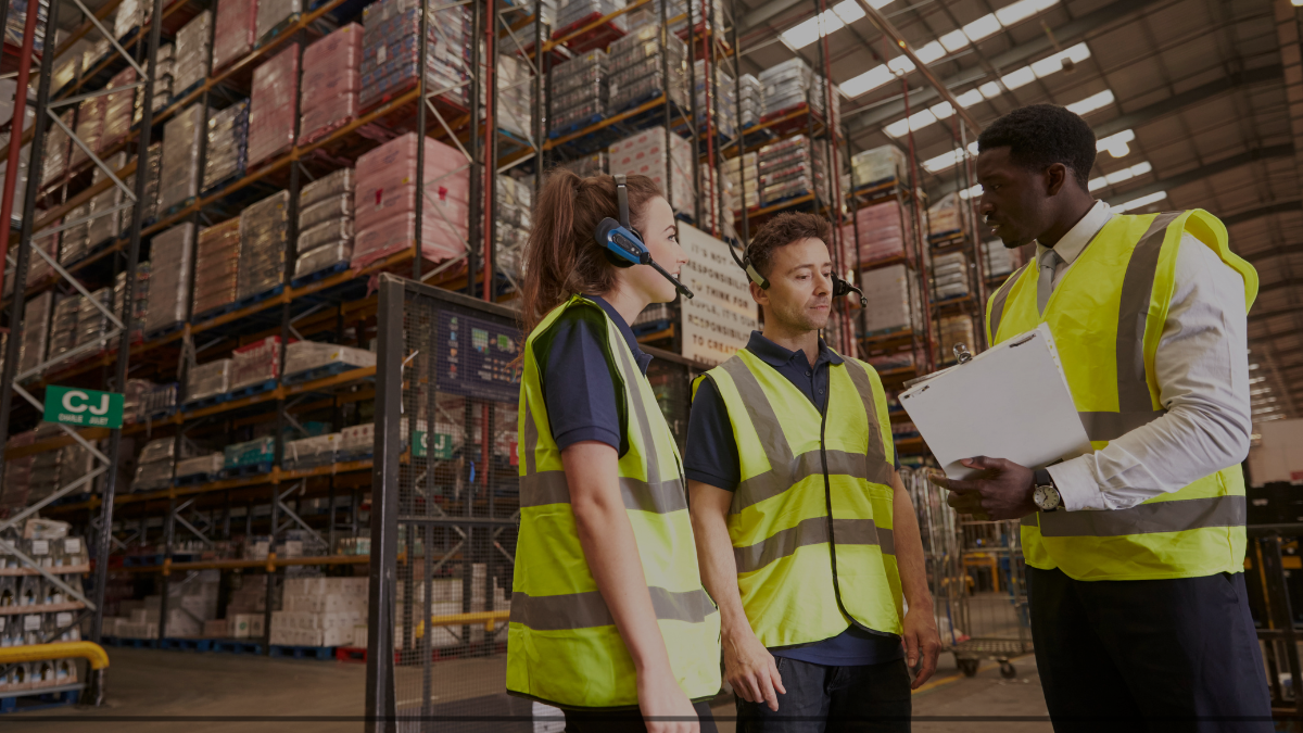Three workers in safety vests discussing over a document at a worksite.